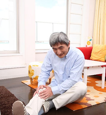 変形性膝関節症の痛みで膝を抱える男性の写真
